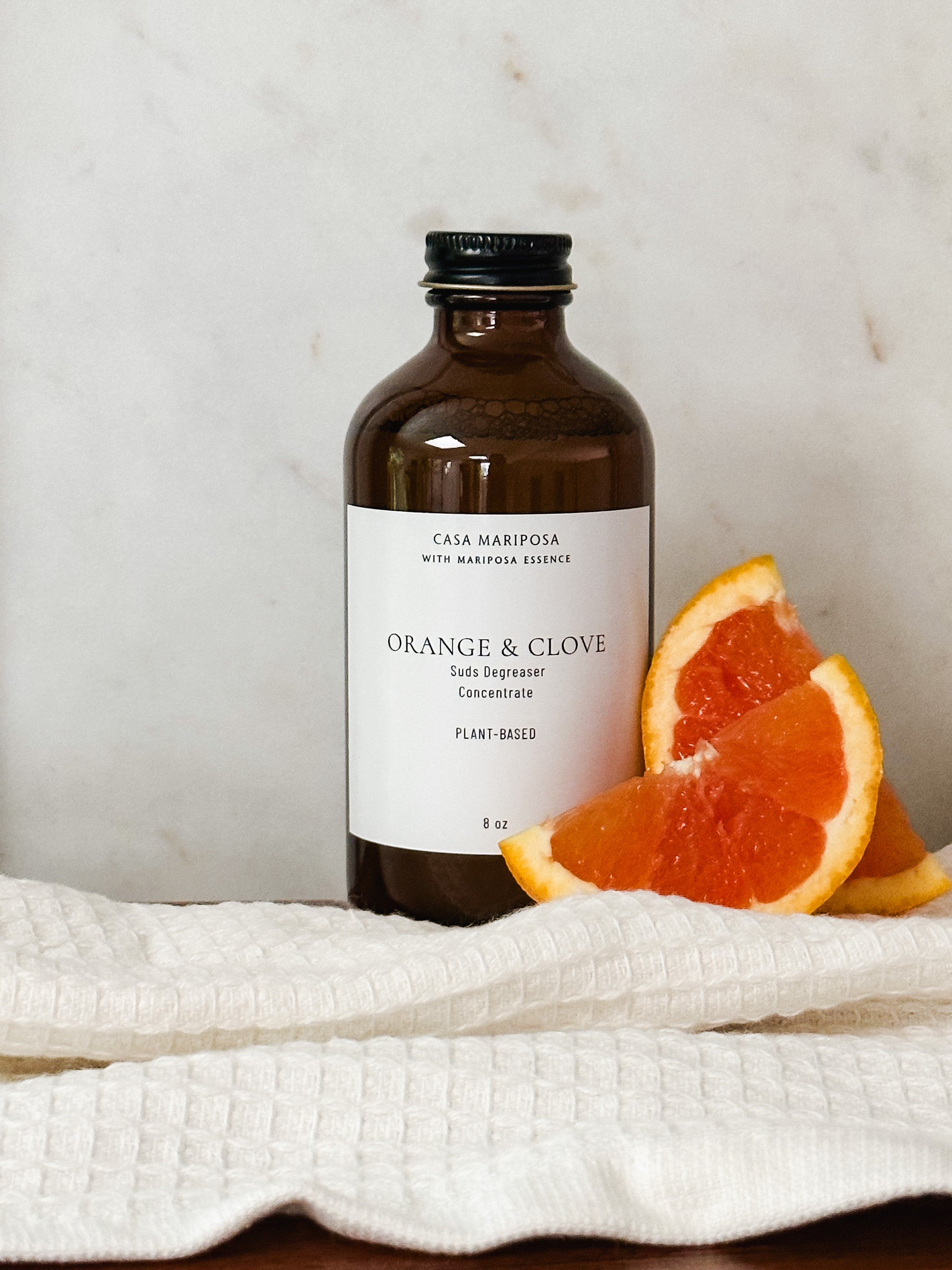 Orange and clove suds degreaser displayed with orange slices.