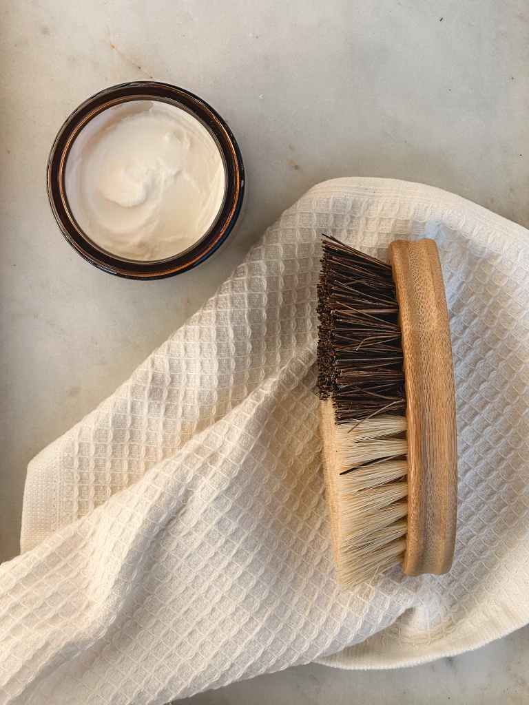 Orange + Clove Suds Scrub displayed with  coconut cleaning brush