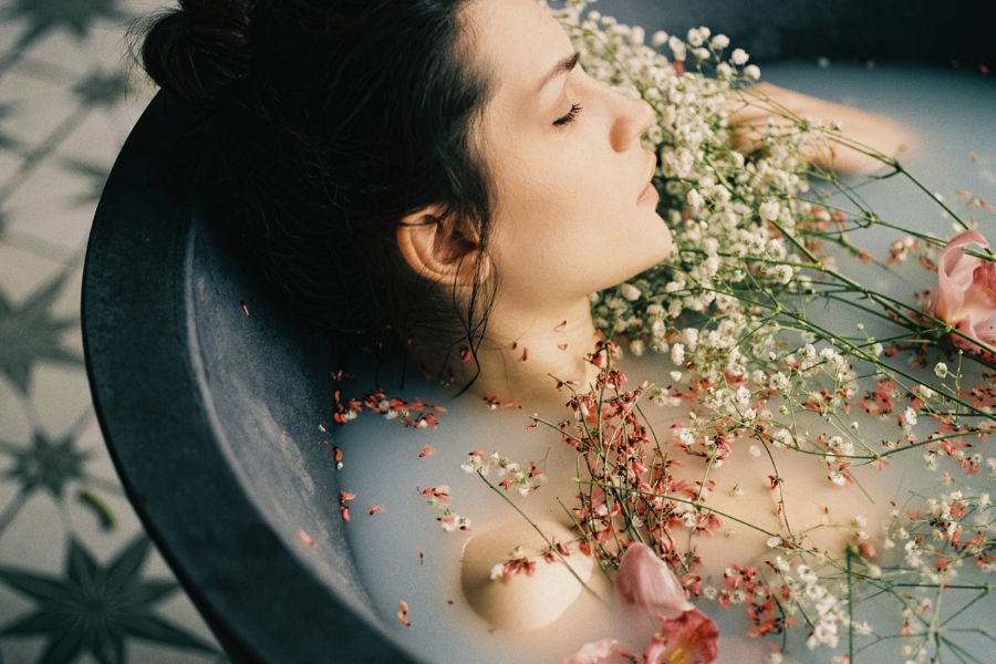 Woman in a bathtub with flowers and candles, surrounded by a warm and intimate atmosphere.
