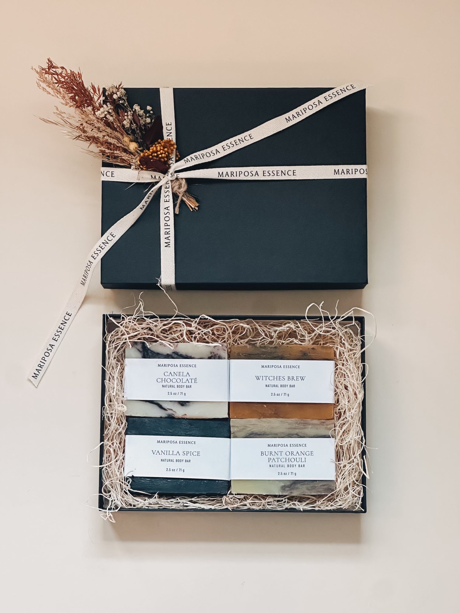 1/2 size body bars in a black box with natural filler and a small bundle of dried fall flowers and cotton brand ribbon.  Included are canela chocolate, witches brew, vanilla spice and burnt orange patchouli.